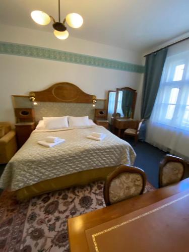 a bedroom with a bed and a table at Hotel Kapitán in Žatec