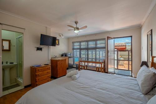une chambre avec un grand lit blanc et une télévision dans l'établissement 5 Third Avenue Guesthouse, à Port Elizabeth