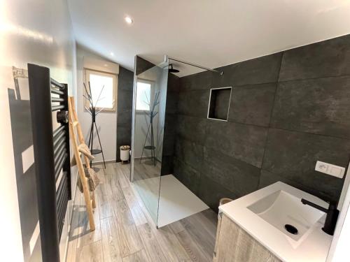 La salle de bains est pourvue d'un lavabo et d'une paroi en verre. dans l'établissement Gîte Figuier - Village De Gîtes, à Rosières