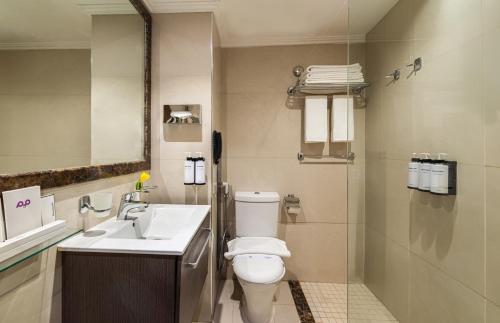 a bathroom with a toilet and a sink and a mirror at Golden Tulip Al-Zahabi in Al Madinah