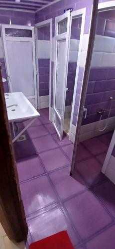 a bathroom with purple tiled floors and a white sink at hostel 1er novembre khenchela in Khenchela