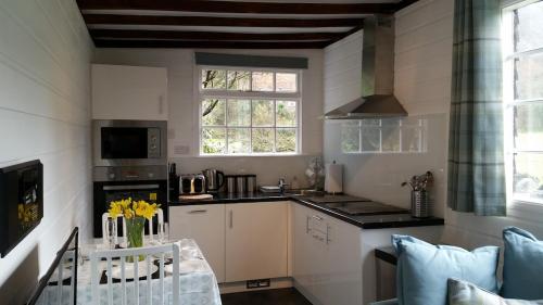 een keuken met witte kasten en een tafel met gele bloemen bij Mountain Lodge, Lake View, National Park in Borrowdale Valley