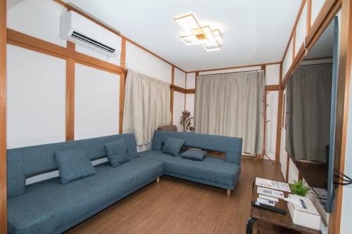 a living room with a blue couch and a tv at NewOpen, Stella Rinku, りんくうタウン駅徒歩10分, 一棟貸切, 関西空港まで6分 in Izumi-Sano