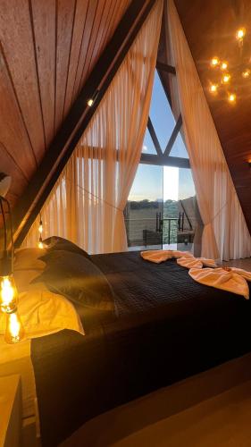 a bedroom with a bed with a large window at Chalé Mirante Morro dos Ventos in Chapada dos Guimarães
