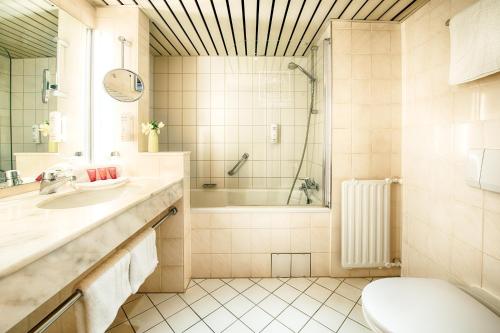 ein Badezimmer mit einer Badewanne, einem WC und einem Waschbecken in der Unterkunft Leonardo Hotel Hamburg City Nord in Hamburg