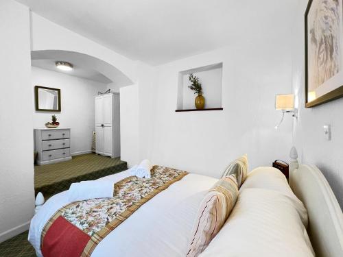 a bedroom with white walls and a bed at Old Coach House Ellicombe in Dunster