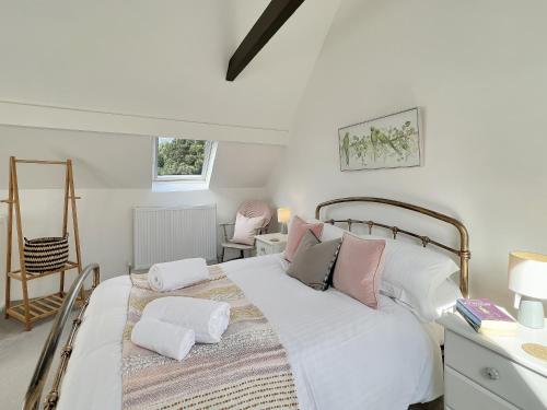 a bedroom with a large white bed with pink pillows at Chapel Cottage Ellicombe in Dunster
