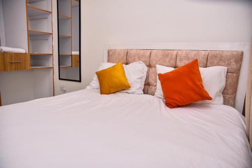 a white bed with two orange pillows on it at Chill Spot Meru in Kaaga