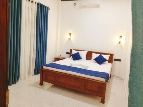 een slaapkamer met een bed met blauwe kussens bij SandaLuck House Ahangama in Ahangama