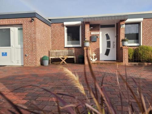 ein Backsteinhaus mit einer Bank davor in der Unterkunft Ferienhaus Düne 16 in Berumbur