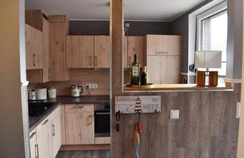 eine Küche mit Holzschränken und einer Flasche Wein in der Unterkunft Ferienhaus Düne 16 in Berumbur