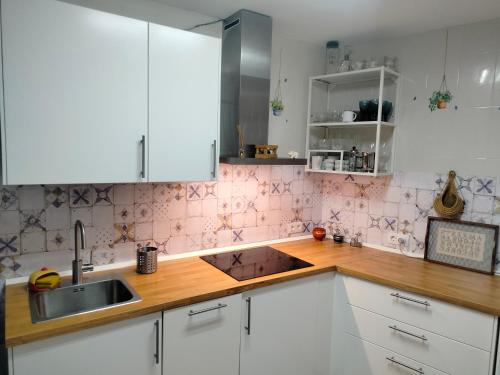 Una cocina con gabinetes blancos y un fregadero. en Casa Fuente del Caño, en Casarabonela