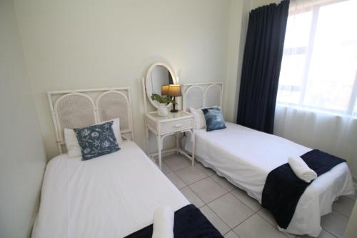 two beds in a room with a mirror and a window at La Corsica 17, Uvongo in Margate