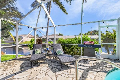 a patio with chairs and a grill next to a swimming pool at Coral Canal Cove in Cape Coral