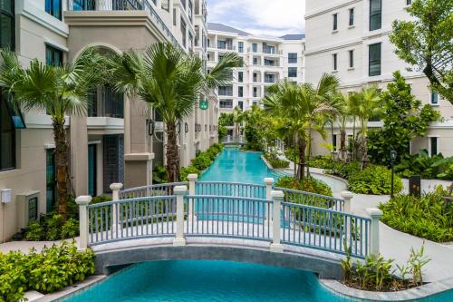 un puente sobre una piscina con palmeras y edificios en The Title Legendary Bangtao by Beringela, en Bang Tao Beach