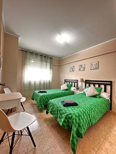 deux lits dans une chambre avec des draps verts dans l'établissement DUPLEX COMPLETO 8 CAMAS La POBLA LLARGA, à Puebla Larga