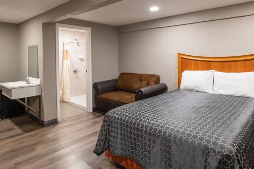 a hotel room with a bed and a chair at Starlite Motel in San Bernardino