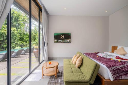 a bedroom with a bed and a green couch at The Garden Villas in Ubud