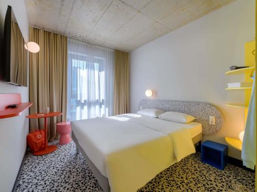 a hotel room with a large bed and a window at ibis budget Münster City in Münster