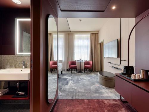a bathroom with a sink and a room with a table at Novotel Münster City in Münster