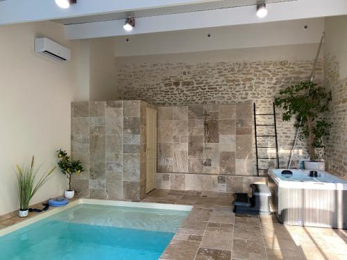 a swimming pool in a room with a stone wall at Chambre L Écrin Végétal piscine spa et petit déjeuner au Château des Bourdons in Varennes Vauzelles