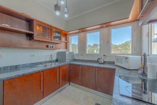 eine große Küche mit Holzschränken und Fenstern in der Unterkunft Beautiful 4 BDR Villa With Private Pool in Hurghada