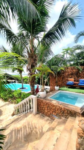 uma casa com piscina e uma palmeira em SunSeaBar Beach Resort em Kendwa
