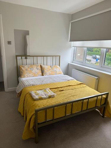 a bedroom with a bed with a yellow blanket and a window at COSY Rooms in Grove Park