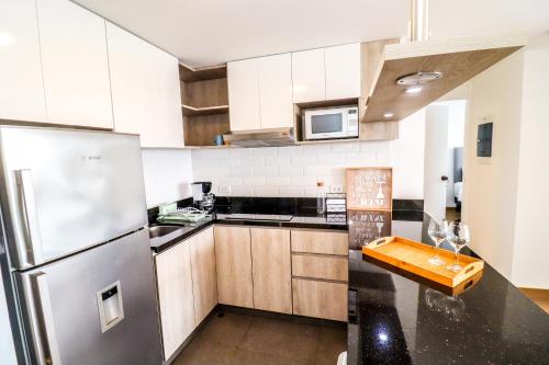 a kitchen with white cabinets and a stainless steel refrigerator at Vive y trabaja con estilo en San Miguel, moderno departamento de 2 dorms con balcon in Lima