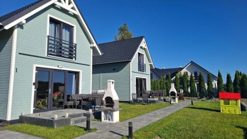 een blauw huis met tafels en stoelen in de tuin bij Domki Morskie Jastrzębia Góra - Domki z basenem in Jastrzębia Góra