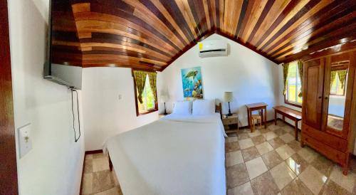a bedroom with a bed and a wooden ceiling at Colinda Cabanas in Caye Caulker
