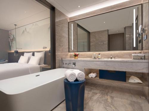 a bathroom with a bed and a tub and a sink at Pullman Huai'an in Huai'an