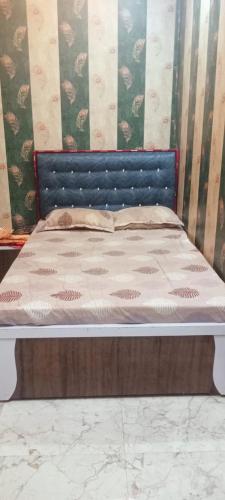 a bed with a blue headboard in a bedroom at Hotel Om in Jaunpur