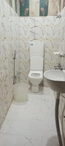 a white bathroom with a toilet and a sink at Hotel Om in Jaunpur