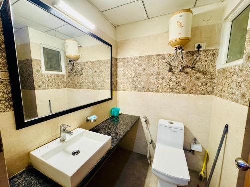 a bathroom with a sink and a mirror and a toilet at Lazy happ stay in Greater Noida