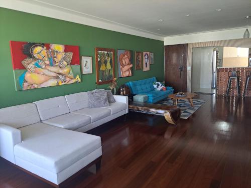 a living room with a white couch and a green wall at Quarto Vista Mar in Recife