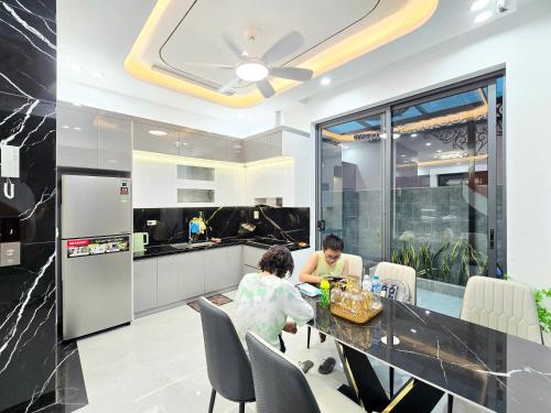 two people sitting at a table in a kitchen at Aura Homestay in Cửu Cảo
