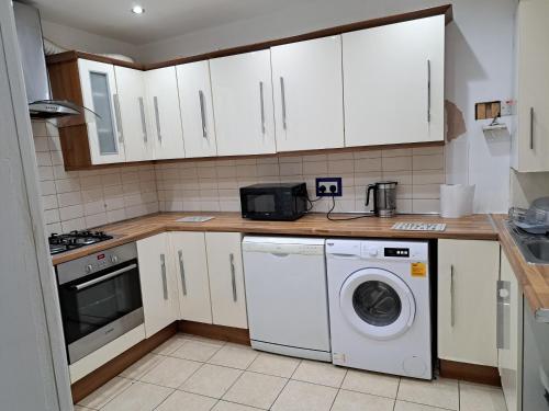 a kitchen with white cabinets and a washing machine at Stretford Residence in Manchester