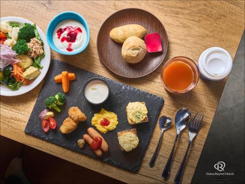 a wooden table with plates of food on it at Daiwa Roynet Utsunomiya in Utsunomiya