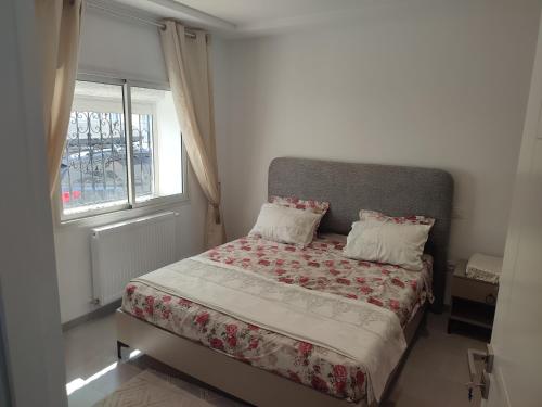 Un dormitorio pequeño con una cama con ventana. en Studio en rez de jardin, en Hammamet