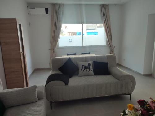 Una sala de estar con un sofá y una ventana. en Studio en rez de jardin, en Hammamet