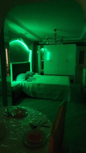 een donkere kamer met twee bedden en een groen licht bij Comfort Apartment Near Staidum in Ganja