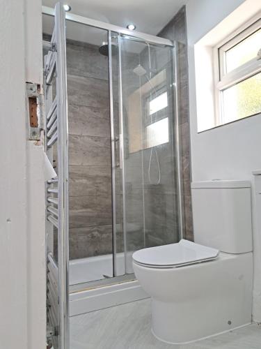 Un baño con inodoro y ducha de cristal. en Stretford Residence, en Mánchester