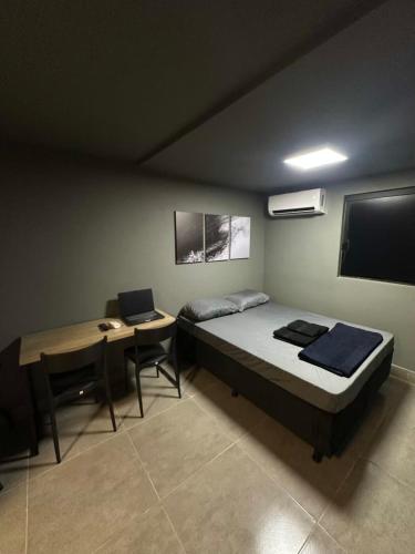 een slaapkamer met een bed en een bureau met een laptop bij Apartmento aconchegante no centro da capital in Brasilia