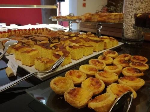 Un buffet de pasteles en bandejas sobre una mesa. en Douro Marina Hotel & SPA, en Resende
