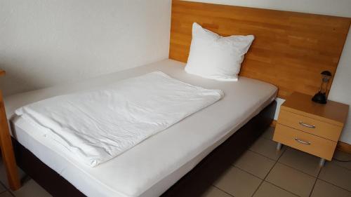 a bed with a white pillow and a wooden headboard at Hotel M Jacobs GmbH in Gummersbach