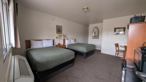 a hotel room with two beds and a television at Himont Motel in Fall River Mills