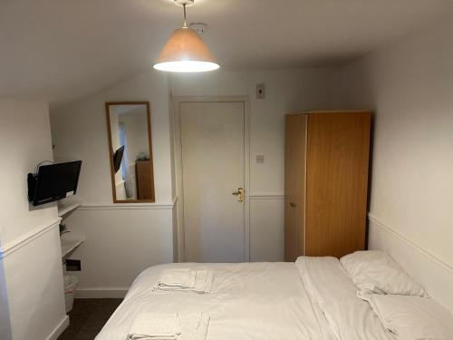 a bedroom with a white bed and a cabinet at Ferryboat Inn in Pangbourne