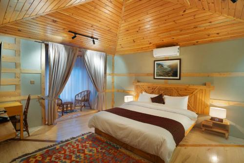 a bedroom with a large bed with a wooden ceiling at Khar Hotel in Skardu