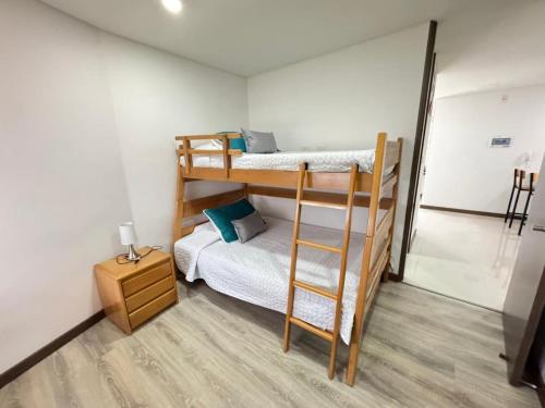 a room with two bunk beds and a night stand at Fundadores Apartment with balcony, pool, gym in Armenia